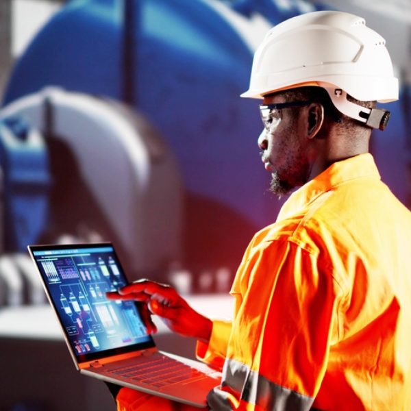 Engineer reviewing technical blueprints alongside an industrial control panel
